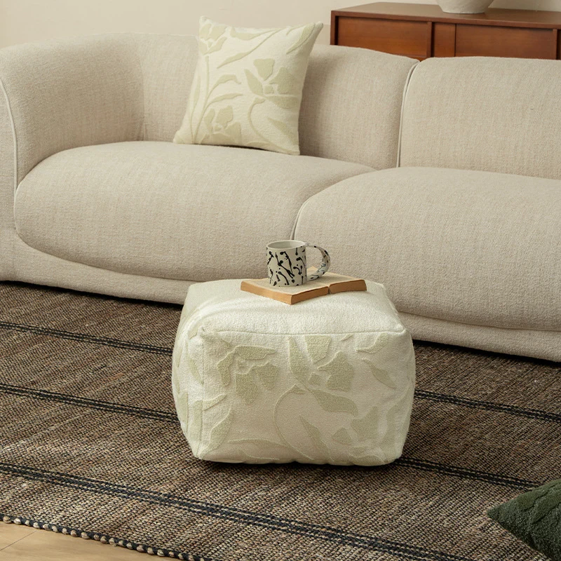 Quadratischer Bodensitzpouf mit strukturierter Bouclé‑Oberfläche und floralem Relief