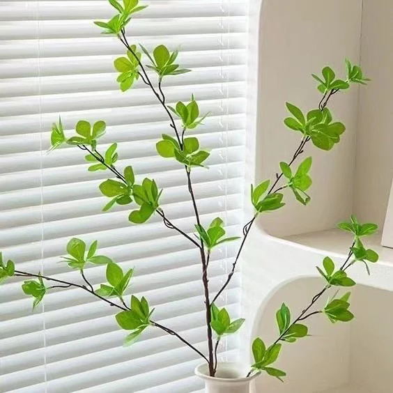 Elegante Glasvase mit lebensechter Grünpflanzenanordnung