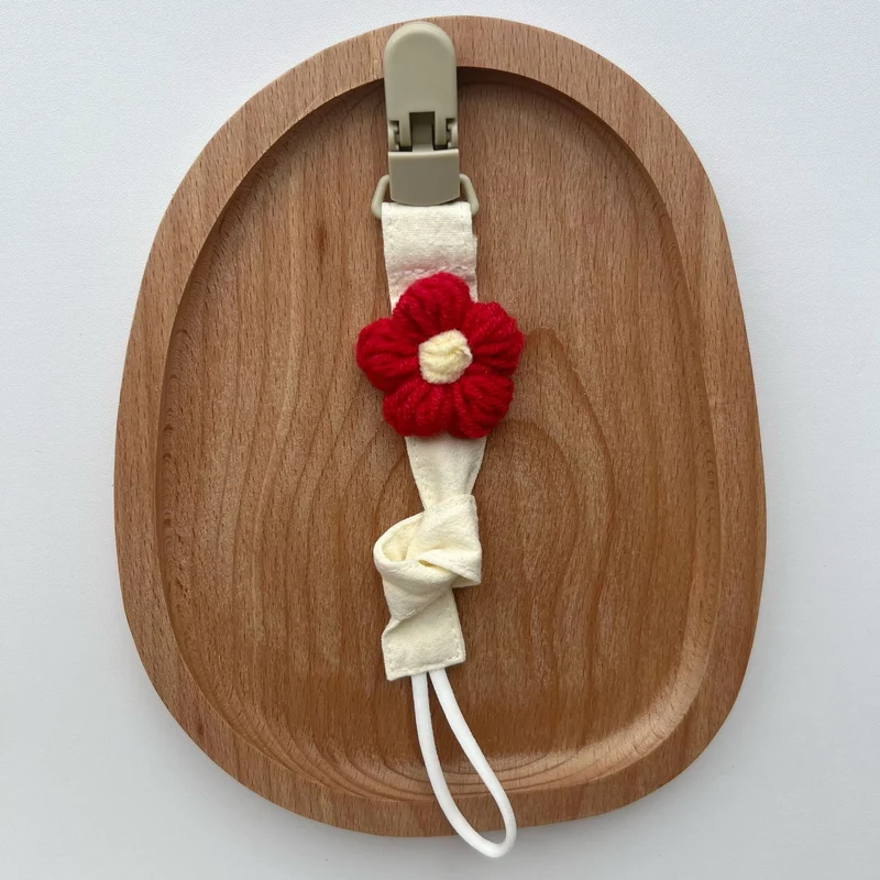 Handgemachter Baumwoll-Schnullerclip mit Gingham-Gurt und gestrickter Blume