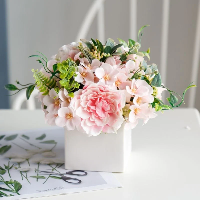 Lebensechte Blumenarrangement in dekorativem quadratischen Pflanzgefäß