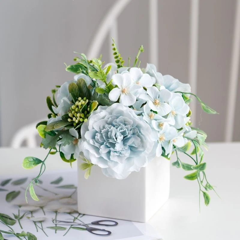 Lebensechte Blumenarrangement in dekorativem quadratischen Pflanzgefäß