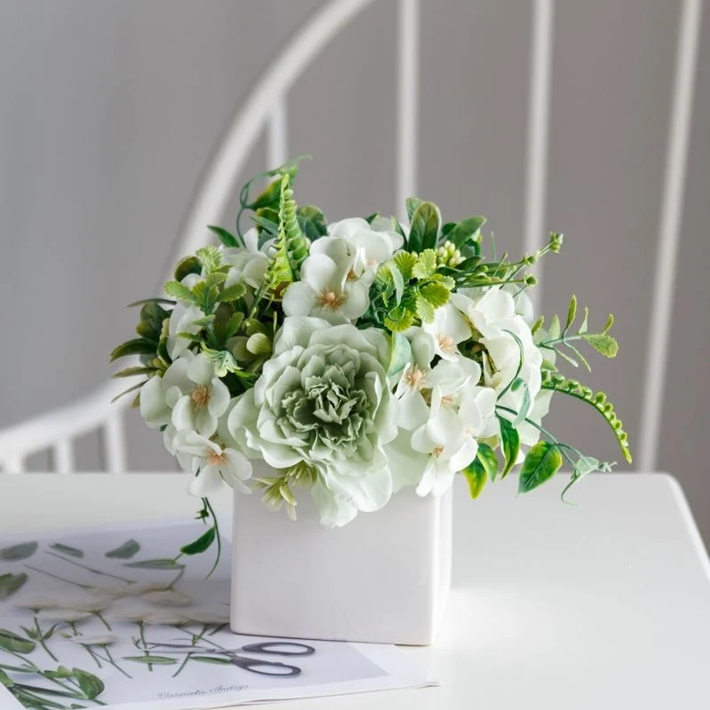 Lebensechte Blumenarrangement in dekorativem quadratischen Pflanzgefäß